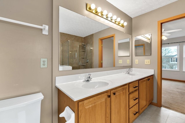 bathroom featuring a sink, a shower stall, a textured ceiling, and double vanity