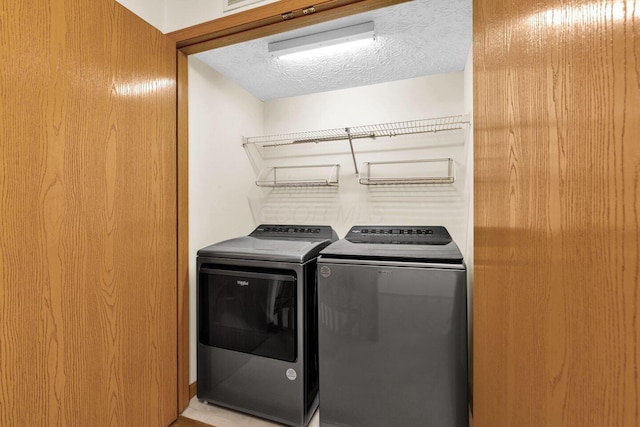 clothes washing area featuring a textured ceiling, laundry area, and washer and clothes dryer