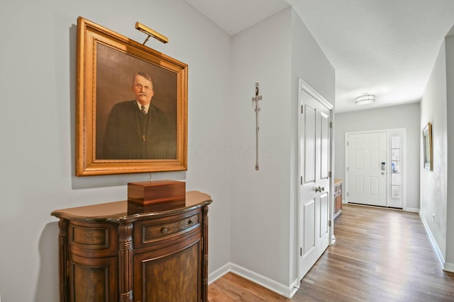 corridor featuring baseboards and wood finished floors