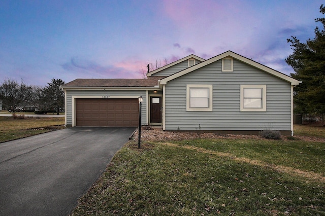 single story home with an attached garage, a front lawn, and aphalt driveway