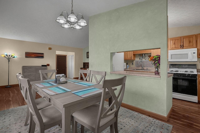 dining space with a textured ceiling, wood finished floors, baseboards, vaulted ceiling, and an inviting chandelier