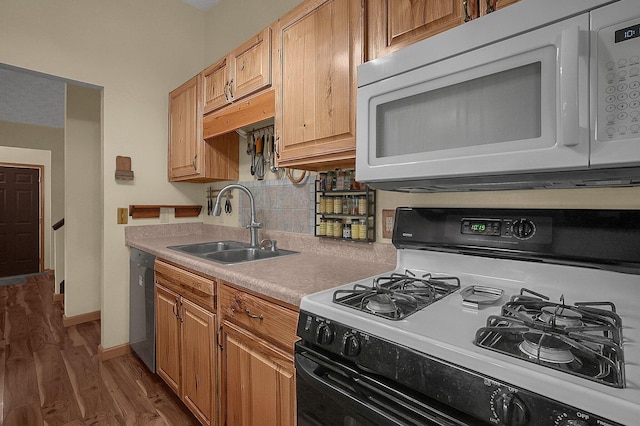 kitchen featuring dishwasher, white microwave, light countertops, a sink, and gas stove