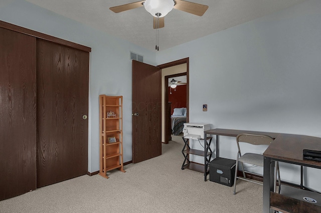 office with light carpet, visible vents, a textured ceiling, and a ceiling fan