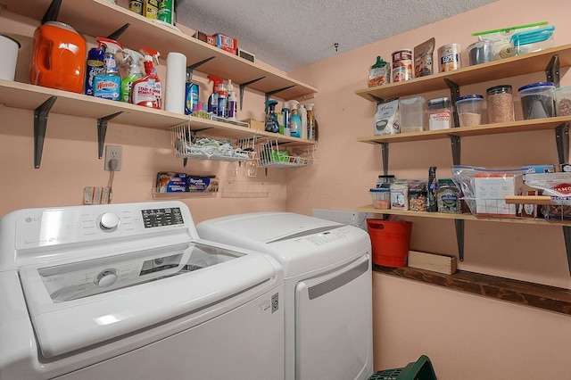 clothes washing area with laundry area, a textured ceiling, and washing machine and clothes dryer