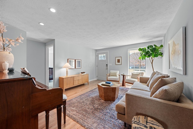 living room with recessed lighting, baseboards, a textured ceiling, and light wood finished floors