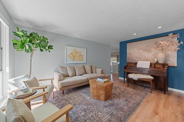 living area with light wood-style floors, baseboards, a textured ceiling, and recessed lighting