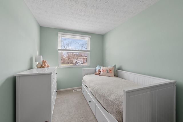 bedroom with light carpet, baseboards, and a textured ceiling