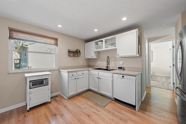 kitchen with light wood finished floors, open shelves, white cabinets, white dishwasher, and a sink