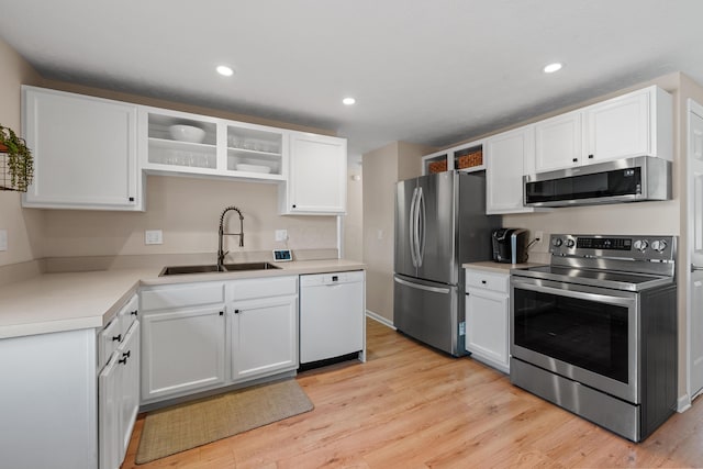 kitchen featuring a sink, white cabinetry, appliances with stainless steel finishes, open shelves, and light wood finished floors