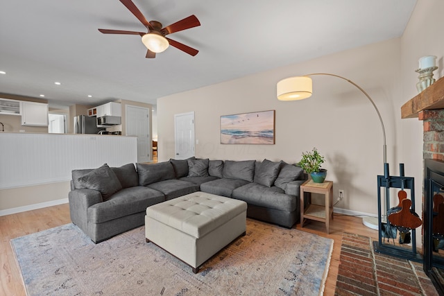 living room with a brick fireplace, baseboards, wood finished floors, and recessed lighting