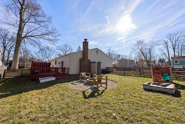 view of yard with fence, a fire pit, and a wooden deck