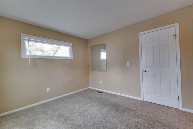 unfurnished room with carpet flooring, visible vents, and baseboards