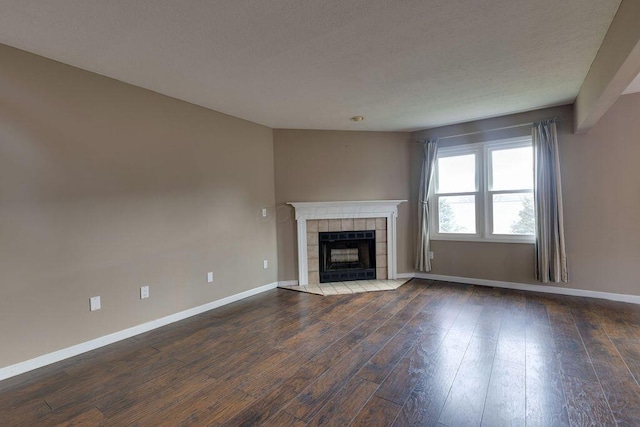 unfurnished living room featuring dark wood-type flooring, baseboards, and a tiled fireplace