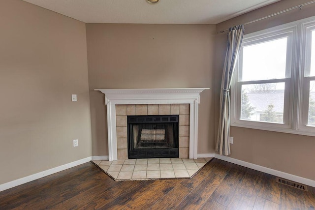 details featuring a tiled fireplace, wood finished floors, visible vents, and baseboards