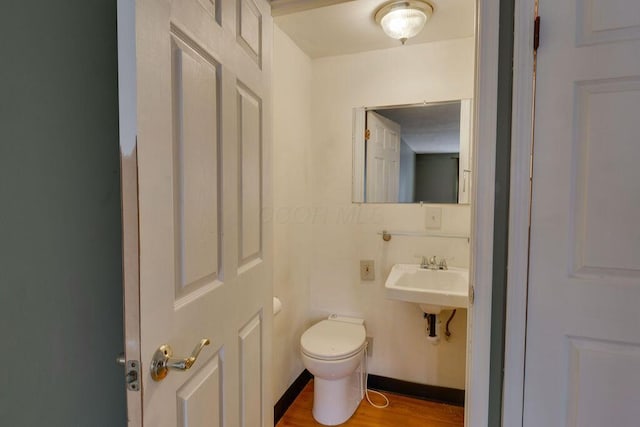 bathroom with a sink, toilet, and wood finished floors