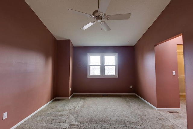 carpeted empty room featuring ceiling fan and baseboards