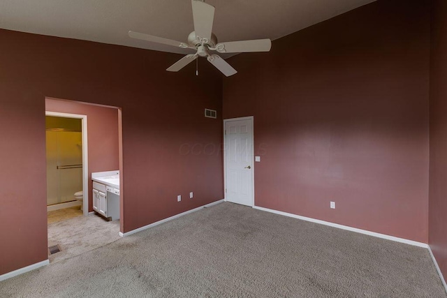 unfurnished bedroom with baseboards, a high ceiling, visible vents, and light colored carpet