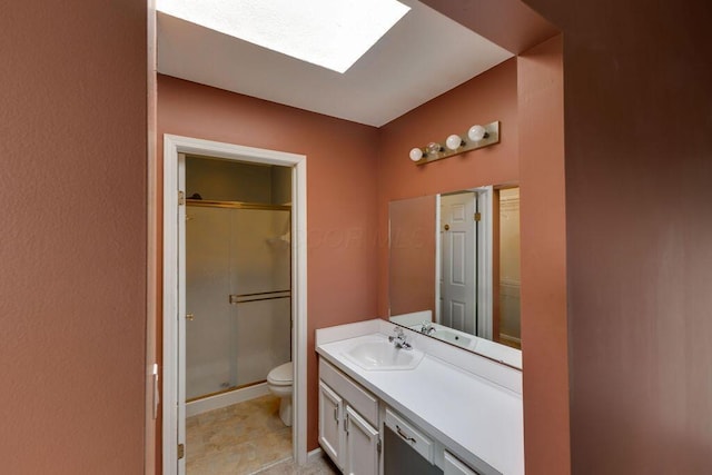 bathroom with a stall shower, a skylight, vanity, and toilet