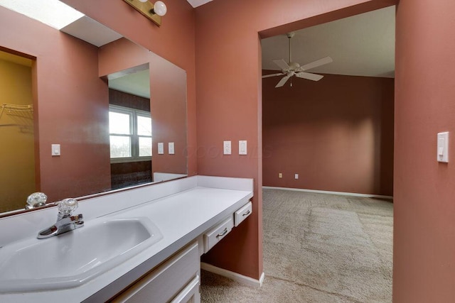 bathroom with a ceiling fan, a walk in closet, vanity, and baseboards