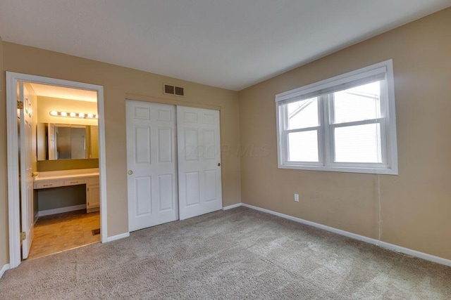 unfurnished bedroom featuring baseboards, visible vents, connected bathroom, light colored carpet, and a closet