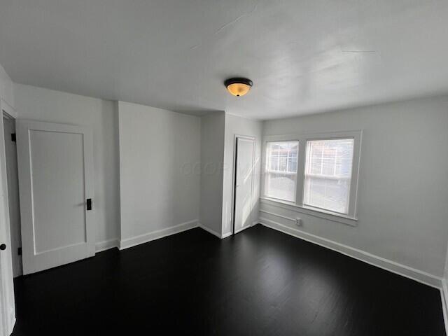 spare room with baseboards and dark wood finished floors