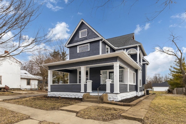 view of front facade featuring covered porch, roof with shingles, and central air condition unit