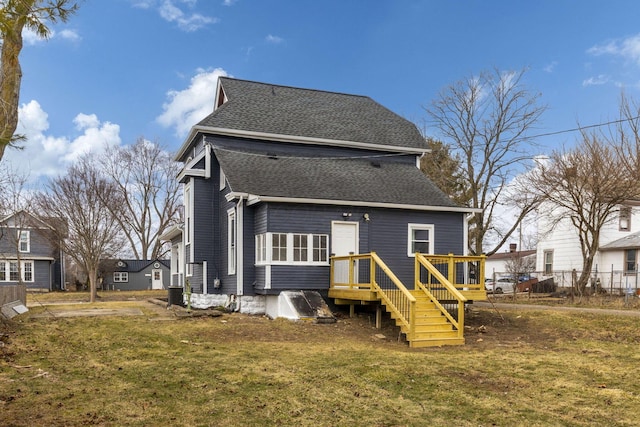 rear view of property with a yard and roof with shingles