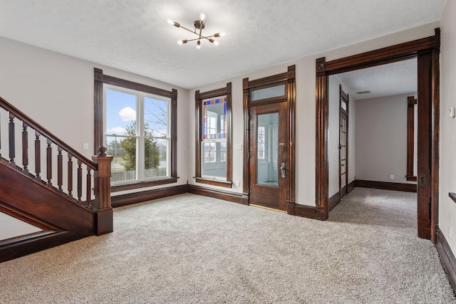 interior space with a notable chandelier, stairs, baseboards, and a textured ceiling