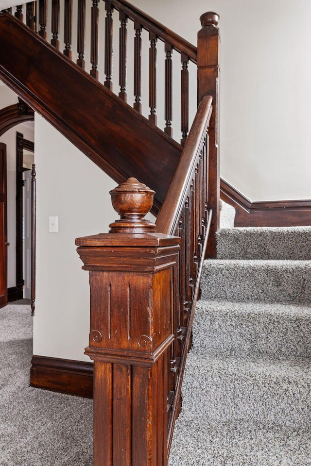 stairs featuring carpet, arched walkways, and baseboards