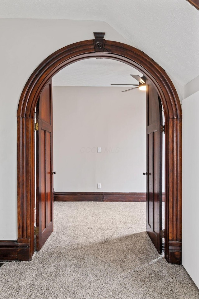 hallway featuring arched walkways and carpet flooring