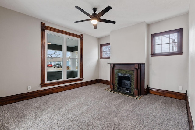 unfurnished living room with carpet floors, a fireplace with flush hearth, a wealth of natural light, and baseboards