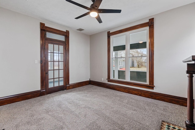 unfurnished room featuring carpet floors, visible vents, baseboards, and a ceiling fan