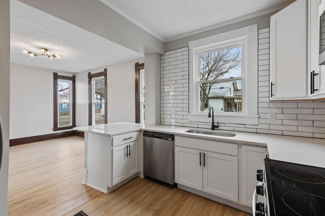 kitchen featuring electric stove, stainless steel dishwasher, light wood-style floors, a sink, and a peninsula