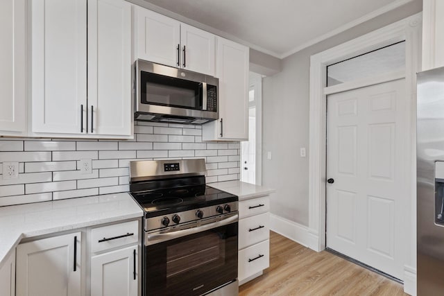 kitchen with tasteful backsplash, light wood-style flooring, appliances with stainless steel finishes, ornamental molding, and white cabinetry