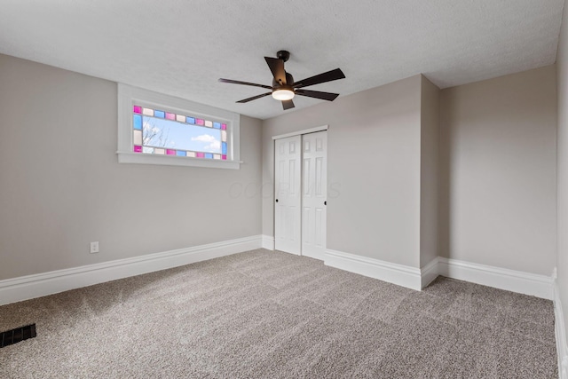 unfurnished bedroom featuring carpet floors, visible vents, a textured ceiling, and baseboards