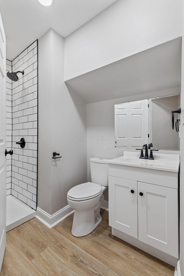 full bathroom featuring toilet, wood finished floors, vanity, baseboards, and a stall shower