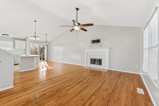 unfurnished living room with visible vents, a healthy amount of sunlight, light wood-type flooring, and a fireplace with flush hearth