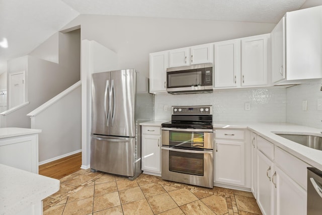 kitchen with white cabinetry, appliances with stainless steel finishes, light countertops, and vaulted ceiling