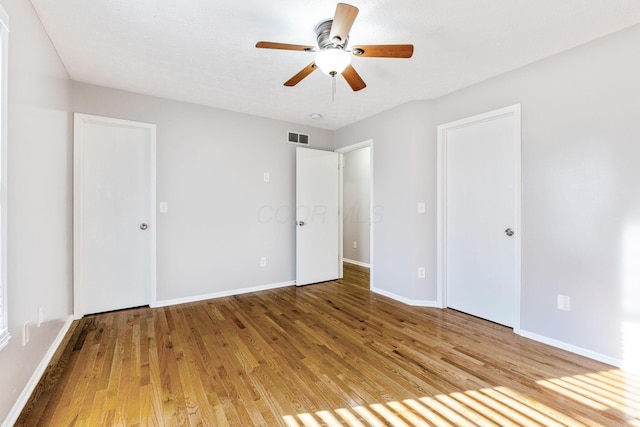 unfurnished bedroom featuring a ceiling fan, wood finished floors, visible vents, and baseboards