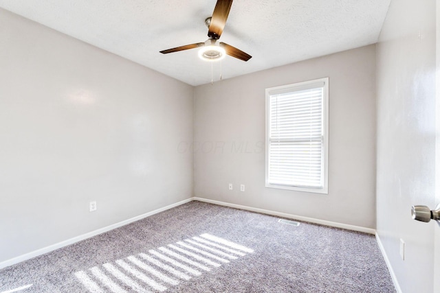 carpeted spare room featuring visible vents, ceiling fan, a textured ceiling, and baseboards