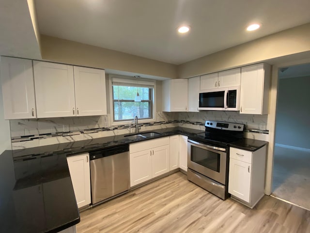 kitchen with backsplash, white cabinetry, stainless steel appliances, and a sink