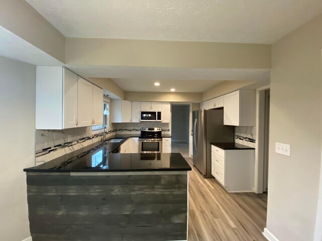 kitchen with a sink, decorative backsplash, white cabinetry, and stainless steel appliances