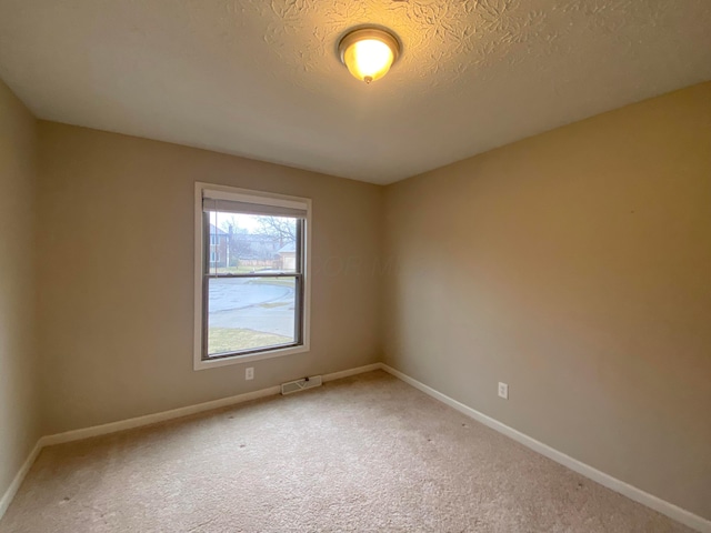 carpeted empty room with visible vents, baseboards, and a textured ceiling