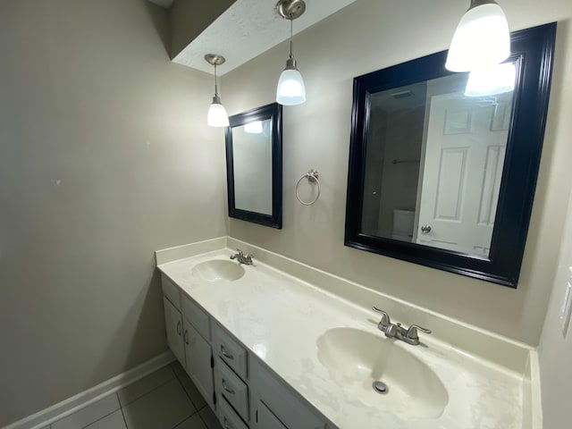 bathroom featuring a sink, baseboards, double vanity, and tile patterned flooring