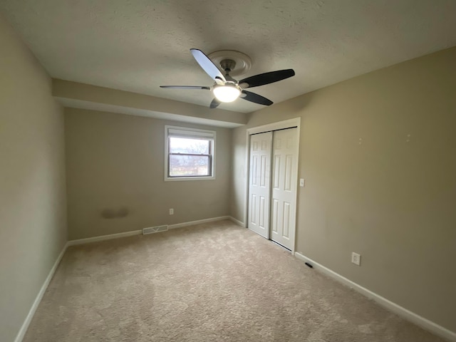 unfurnished bedroom featuring baseboards, a closet, carpet floors, and a textured ceiling