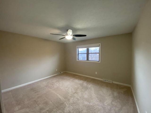 carpeted empty room with a ceiling fan, visible vents, and baseboards