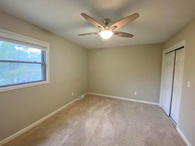 unfurnished bedroom featuring a closet, baseboards, light colored carpet, and visible vents