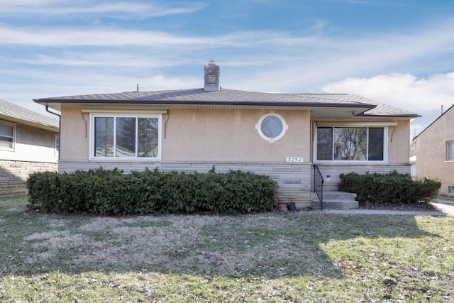 view of front of house featuring stucco siding, a chimney, and a front yard