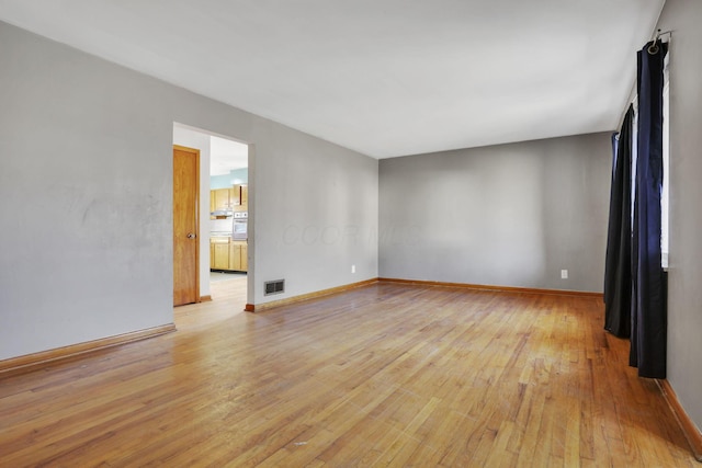 empty room with visible vents, baseboards, and light wood finished floors