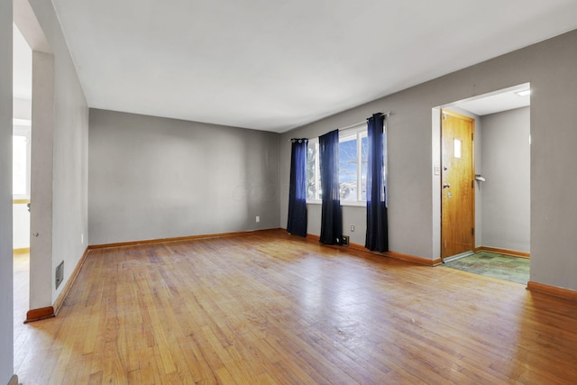 unfurnished room with hardwood / wood-style floors, visible vents, and baseboards